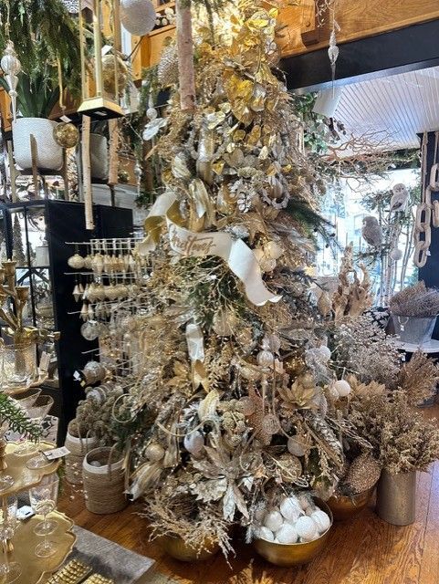 Gold-dusted decorative tree with hanging ornaments and white accents in a shop display