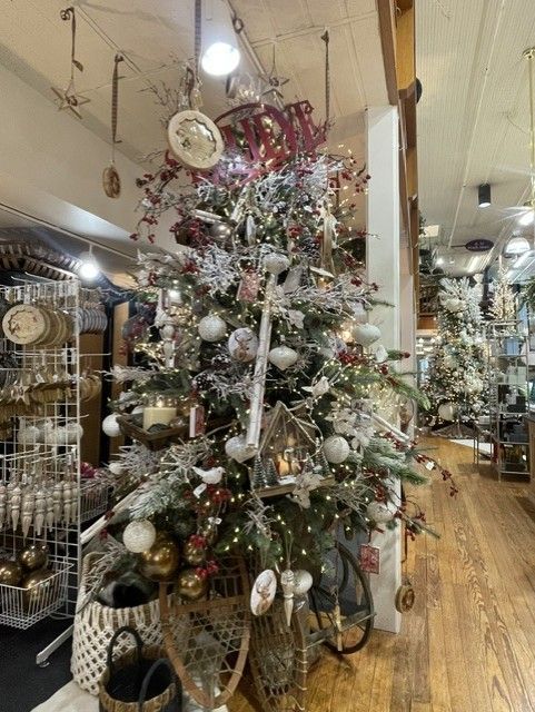 Decorated Christmas tree with silver and white ornaments in a warmly lit home decor shop