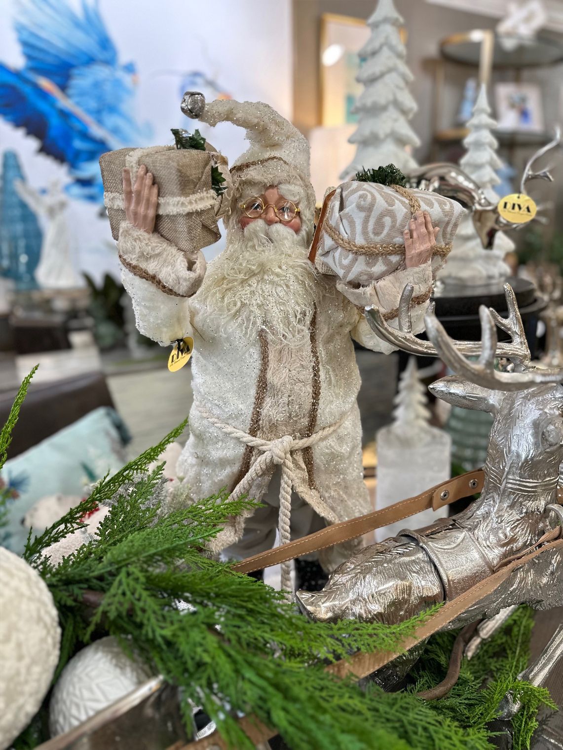 Bearded Santa figurine in a rustic holiday display with greenery, silver antlers, and hanging ornaments.