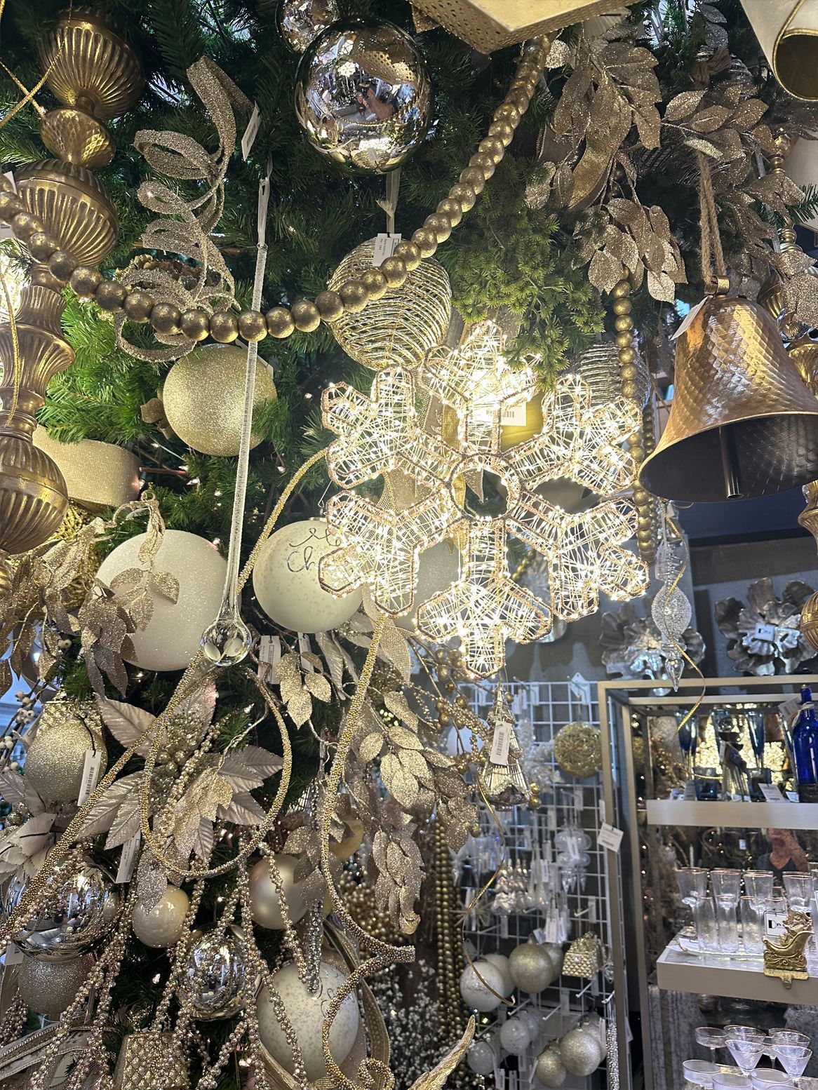 A display of ornate gold and silver holiday ornaments and decorations hanging in a shop.