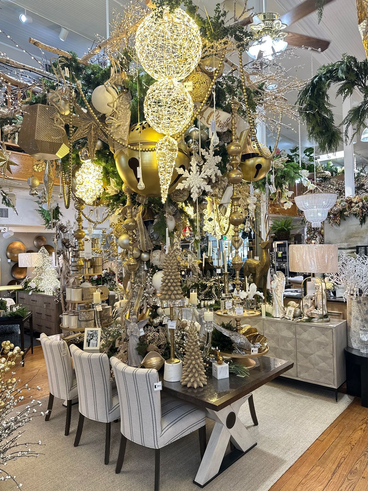 Elegant gold-and-white banquet table with tall floral centerpieces and hanging lights in a decorated event hall