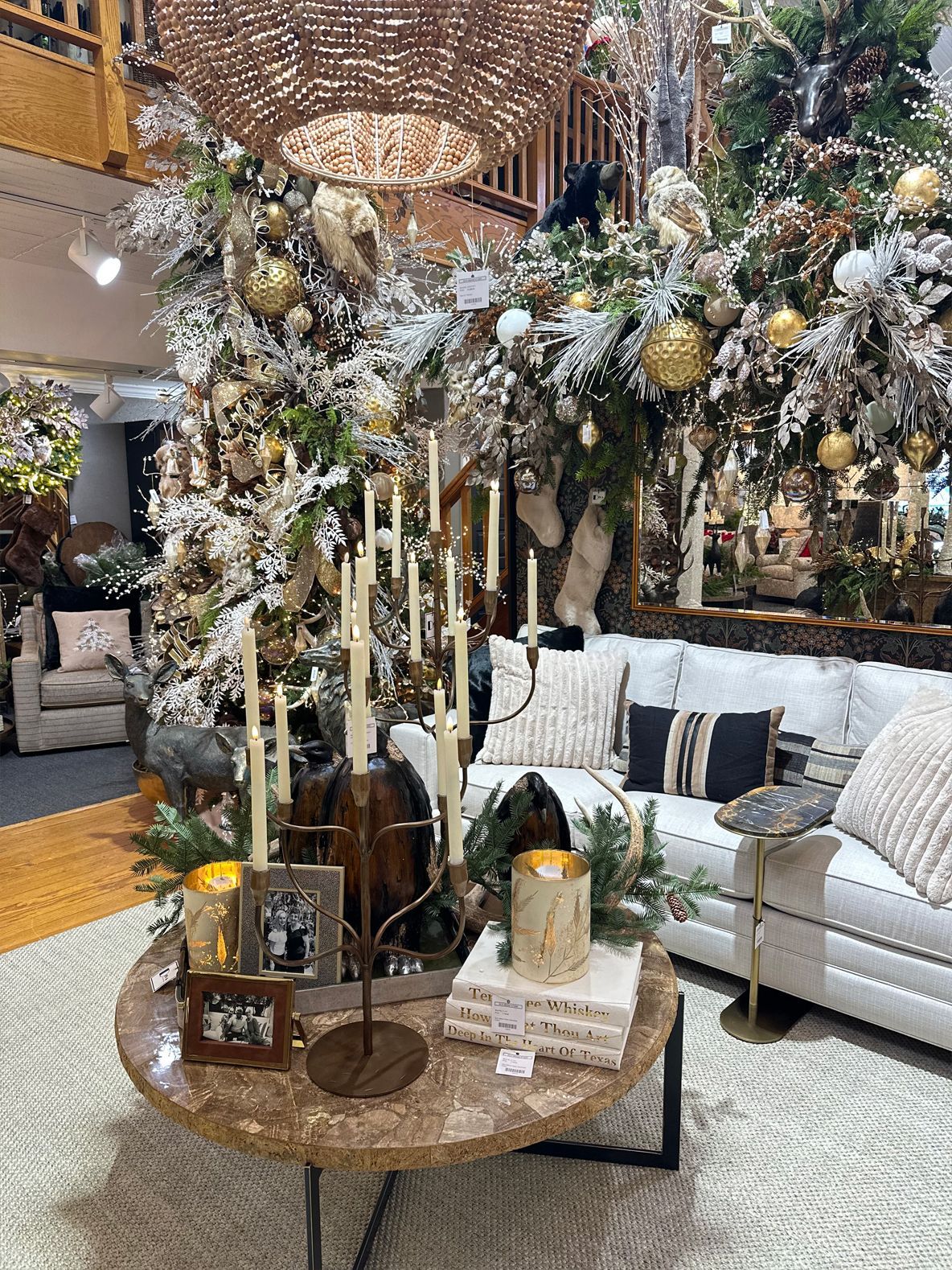Decorated living room with a large gold-and-white holiday tree beside a white sofa and coffee table