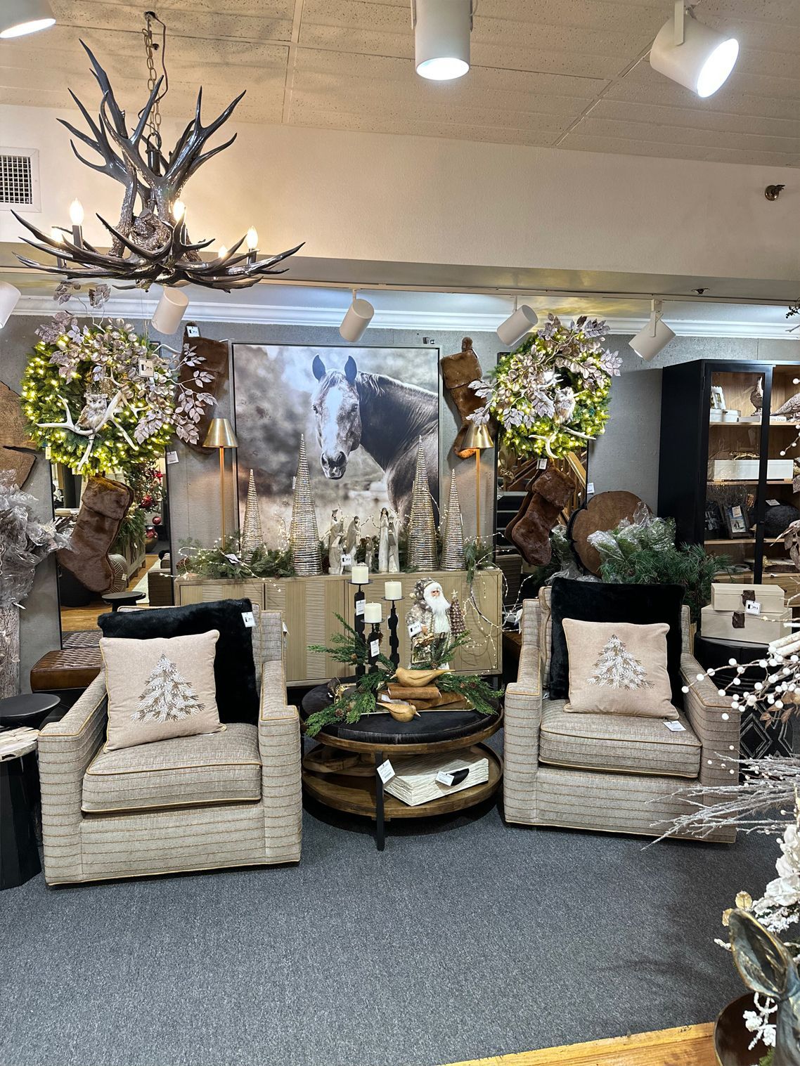 Cozy showroom seating display with two wicker chairs, pillows, a coffee table, and floral decor