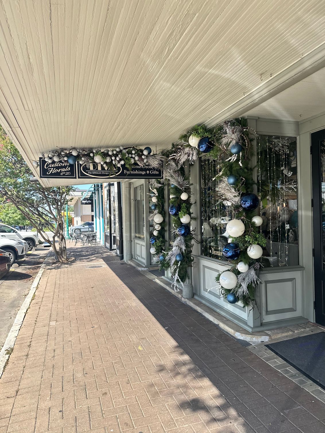 Storefront decorated with blue, white, and silver holiday garlands along a covered sidewalk.