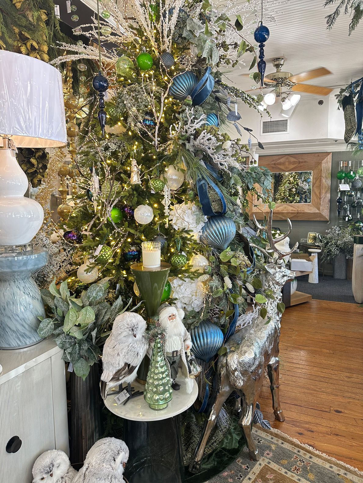 Decorated Christmas tree in a boutique-style room with blue, white, and silver ornaments