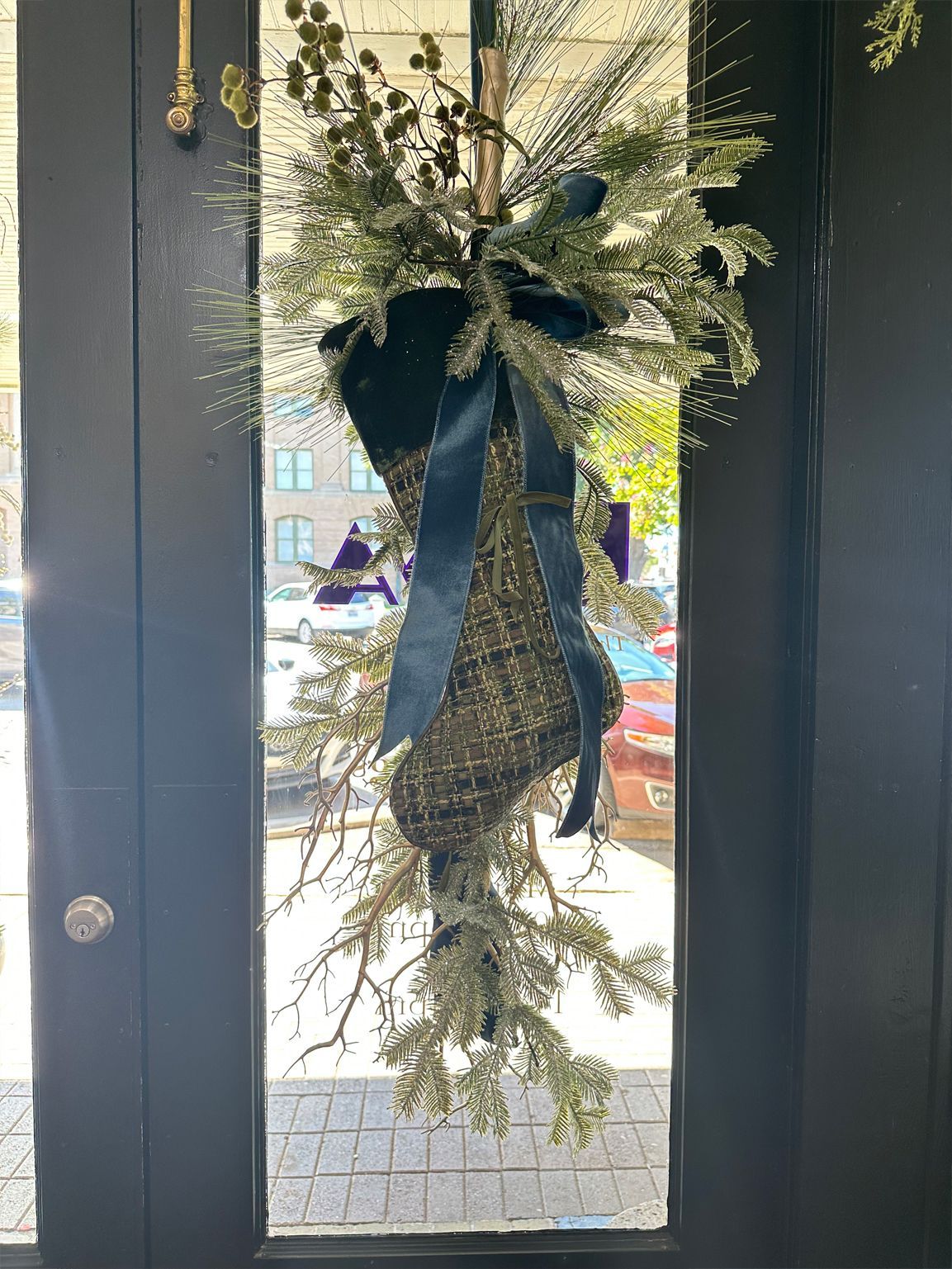 Evergreen holiday wreath with black bow hanging on a glass door