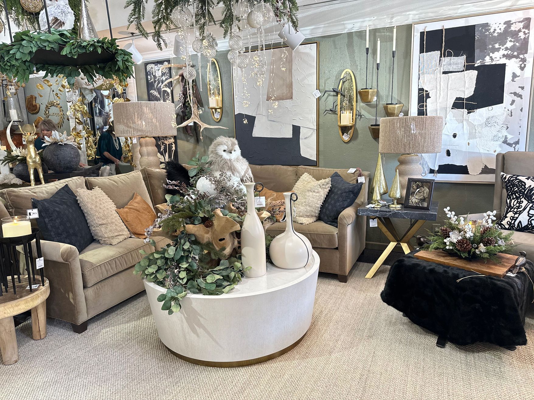 Showroom living room display with beige sofas, round white coffee table, and floral decor