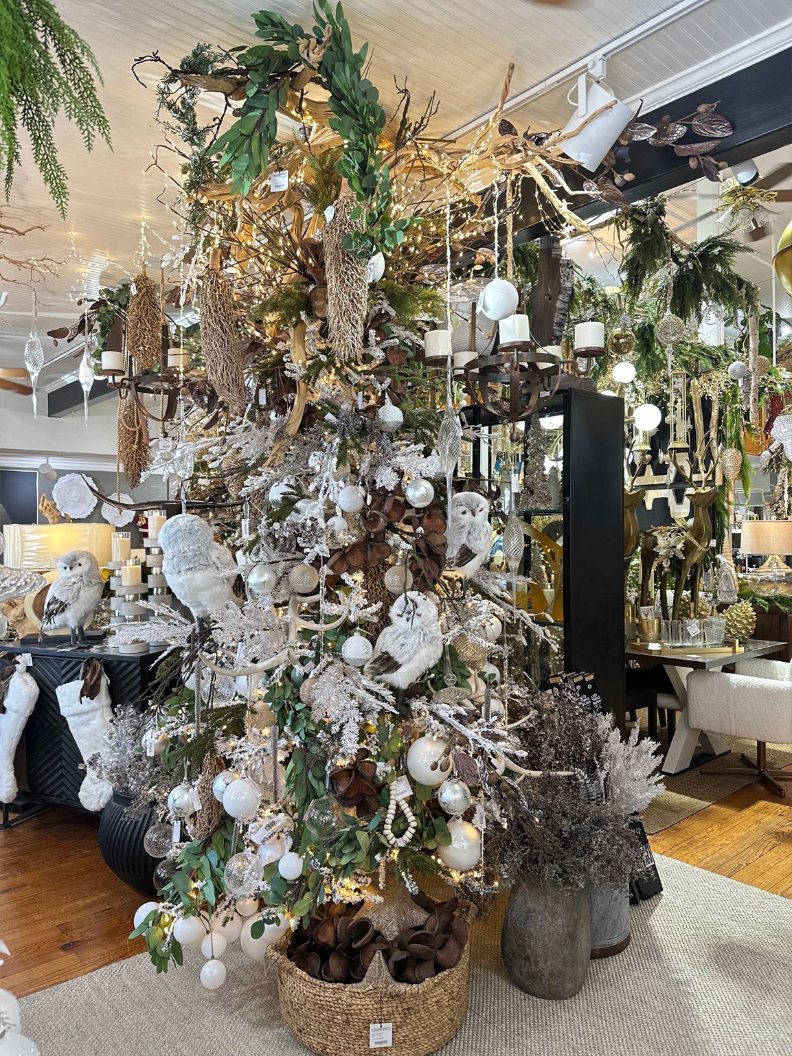 Decorated Christmas tree with white and gold ornaments in a cozy indoor shop display