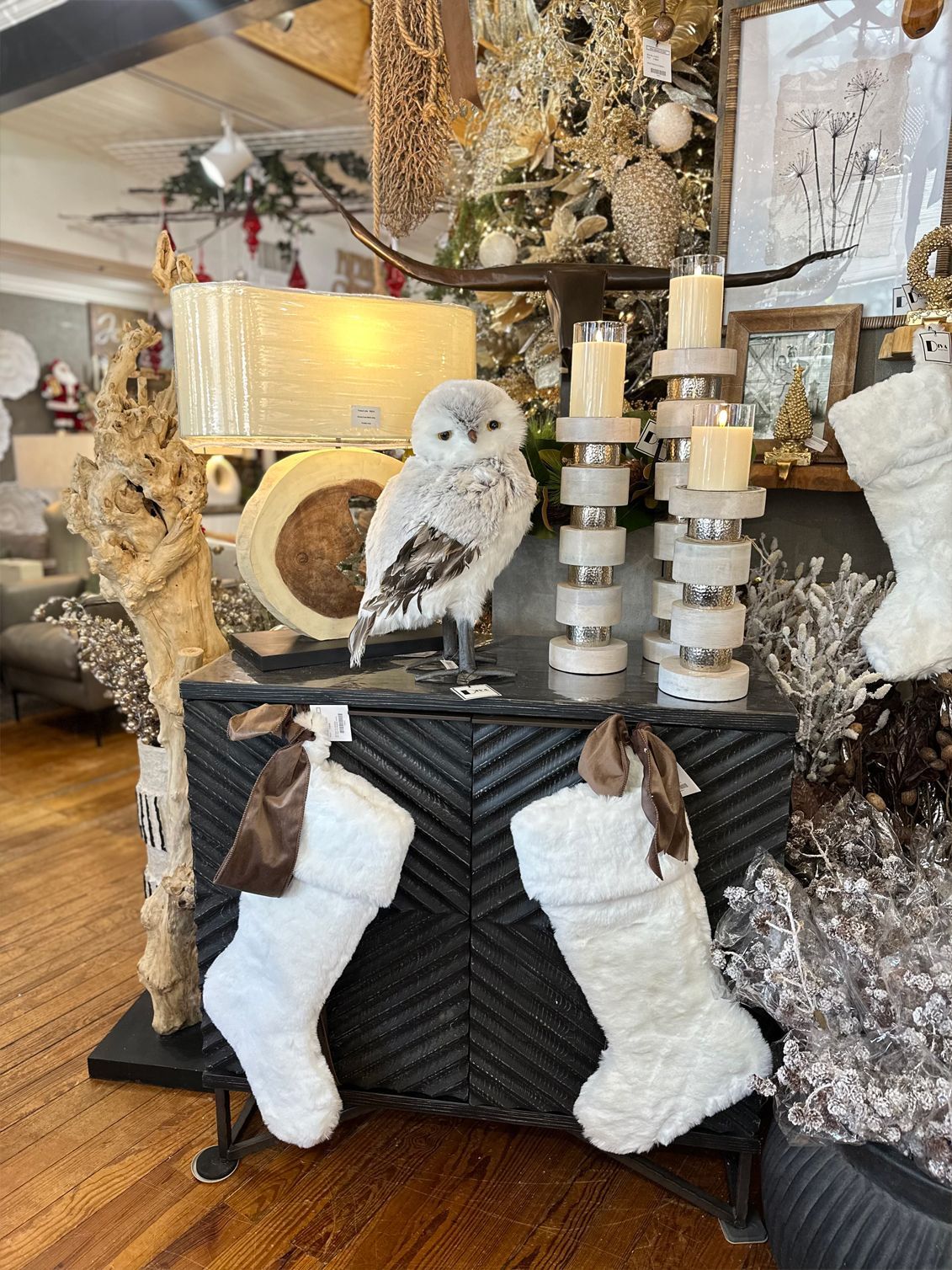 White owl perched on a black mantel among candles, decor, and two hanging stockings in a festive room