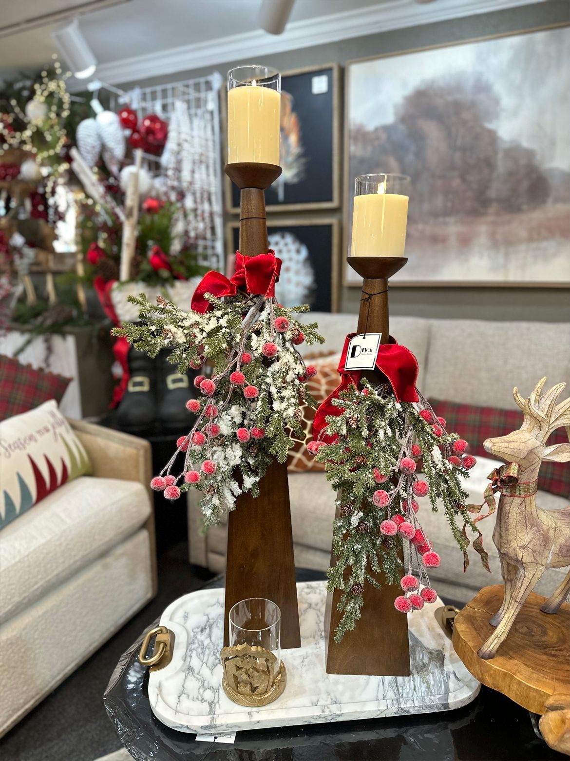 Holiday display with tall wooden candleholders, red roses, and greenery in a living room
