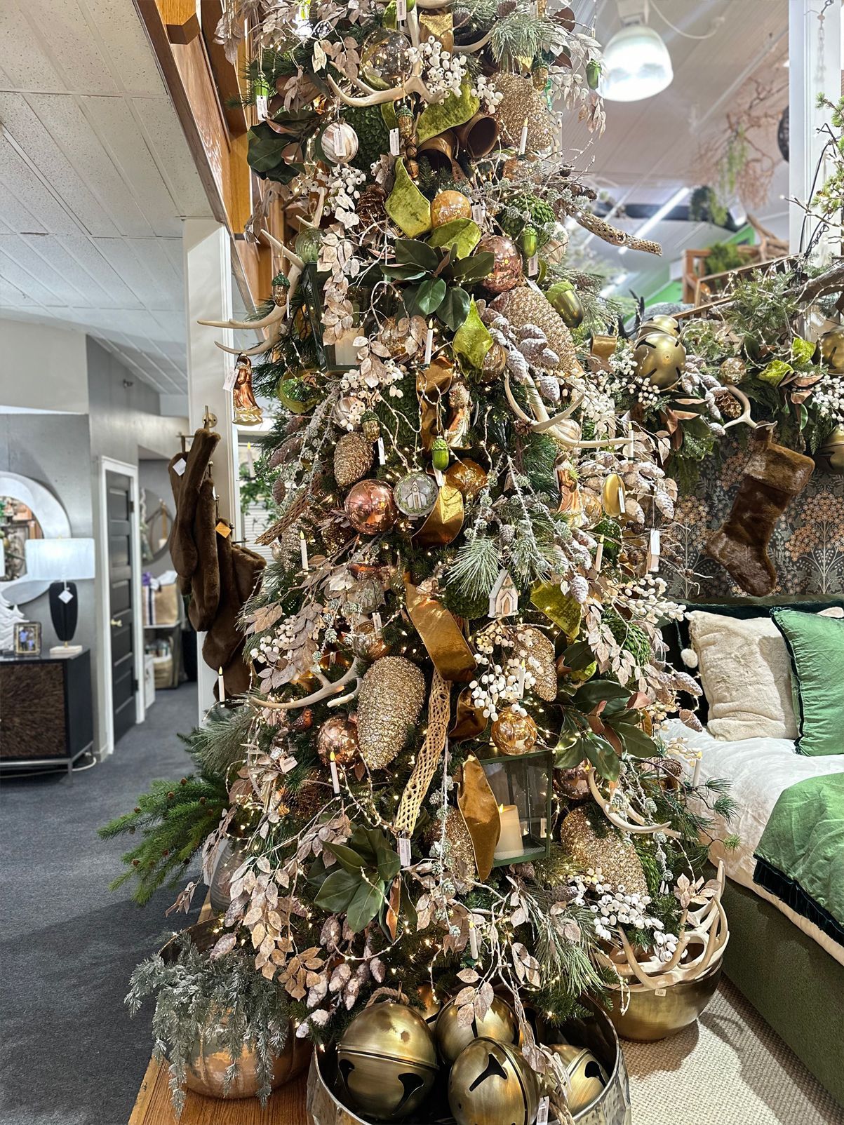Decorated Christmas tree with gold ornaments and greenery in a bright indoor living room