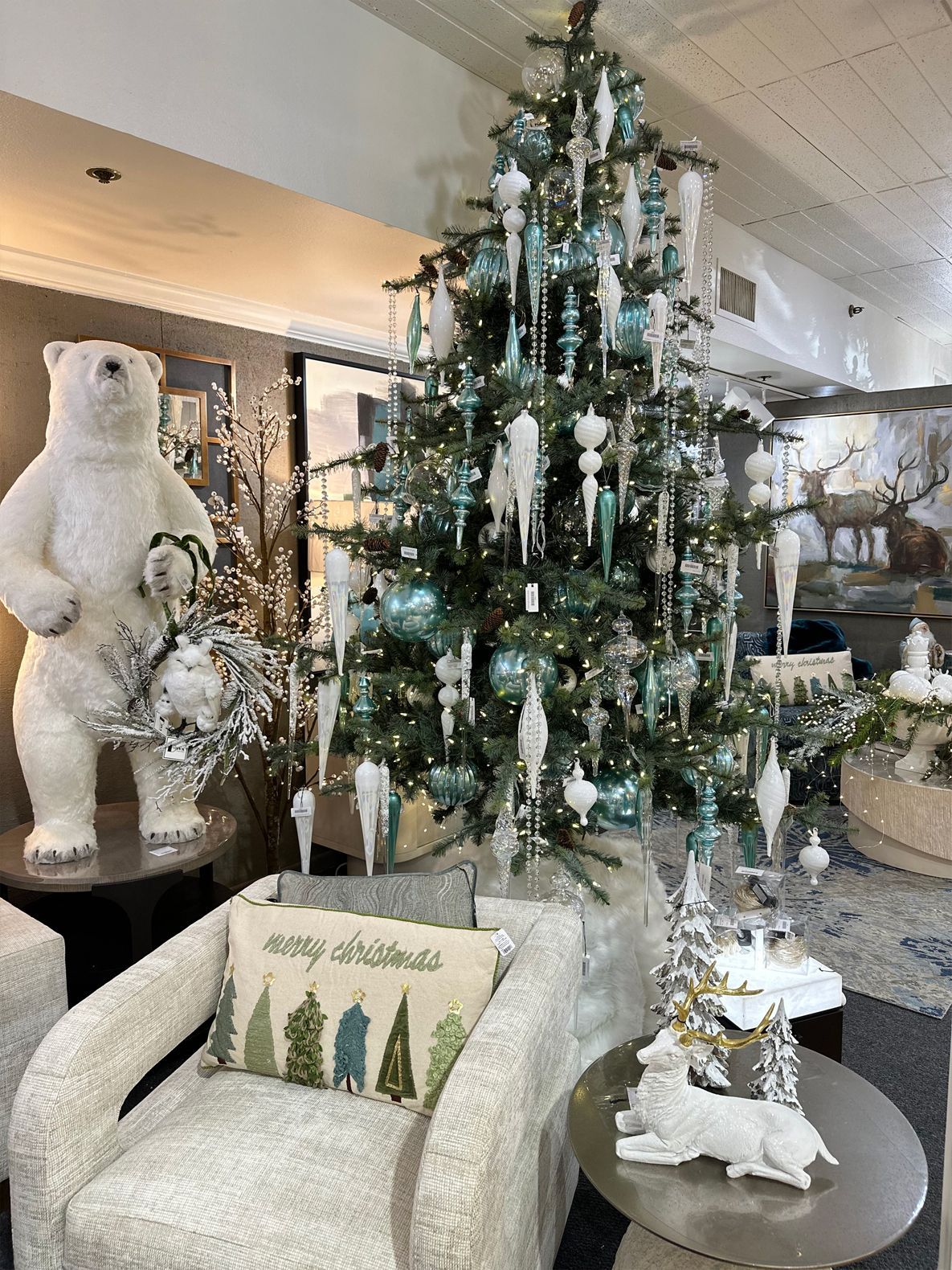 Decorated Christmas tree in a showroom beside a white polar bear display and festive chairs