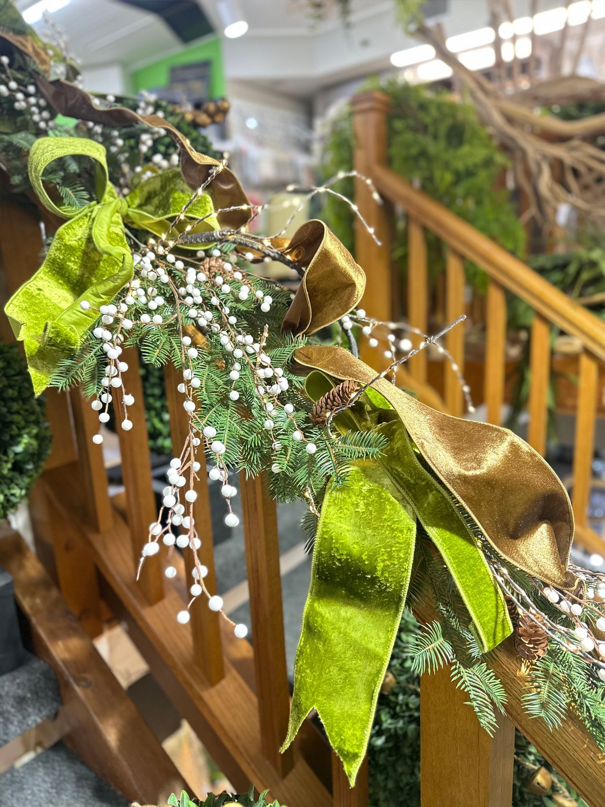 Green and gold ribbon garland with white berries draped over a wooden railing indoors
