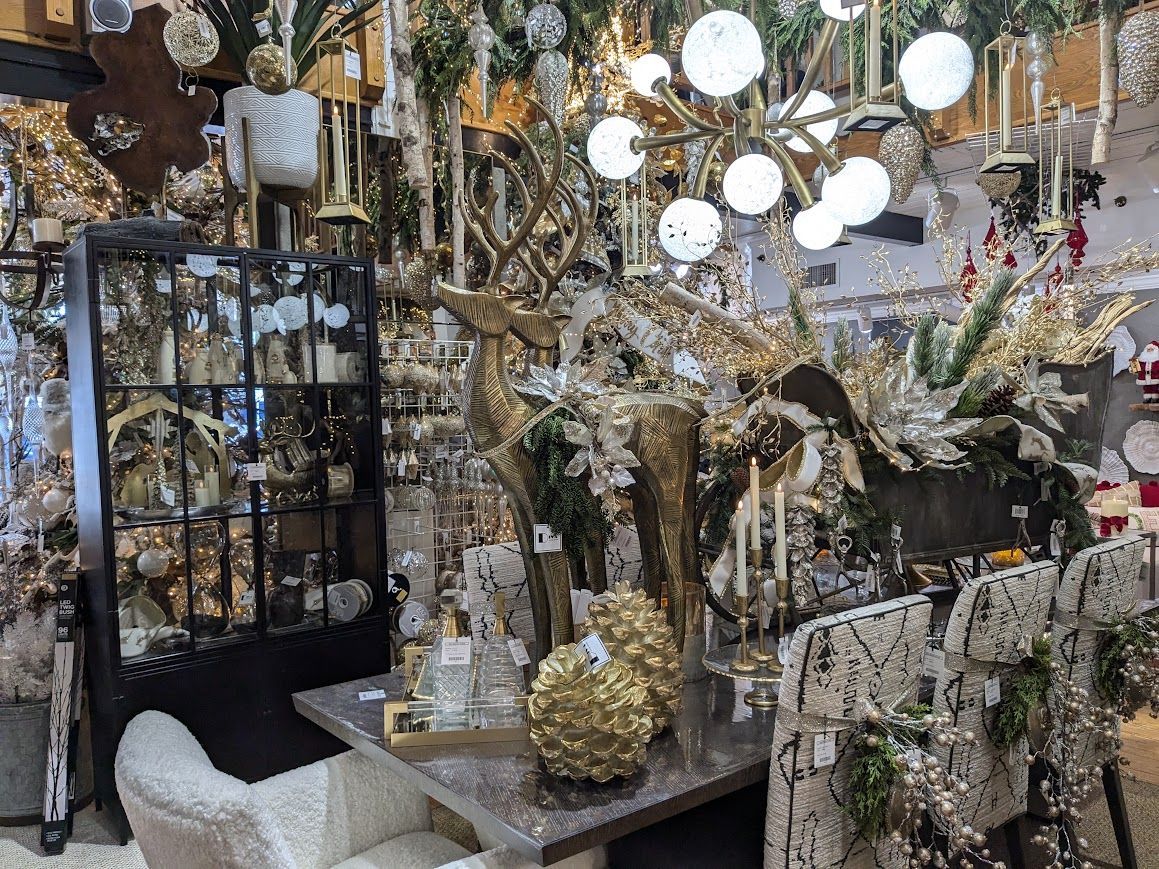 Decorative holiday display with gold and silver ornaments, wreaths, and glowing hanging lights in a shop