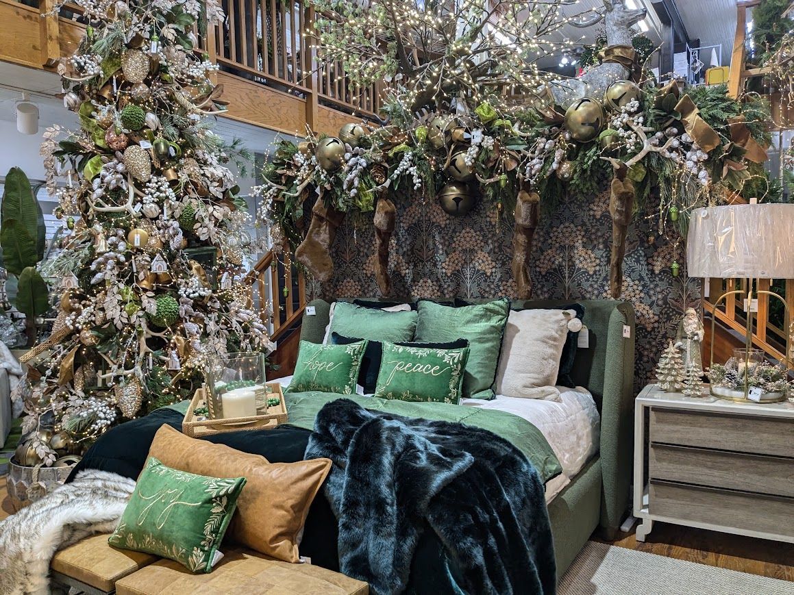 Cozy bedroom with green bedding, faux foliage canopy, and a decorated Christmas tree nearby