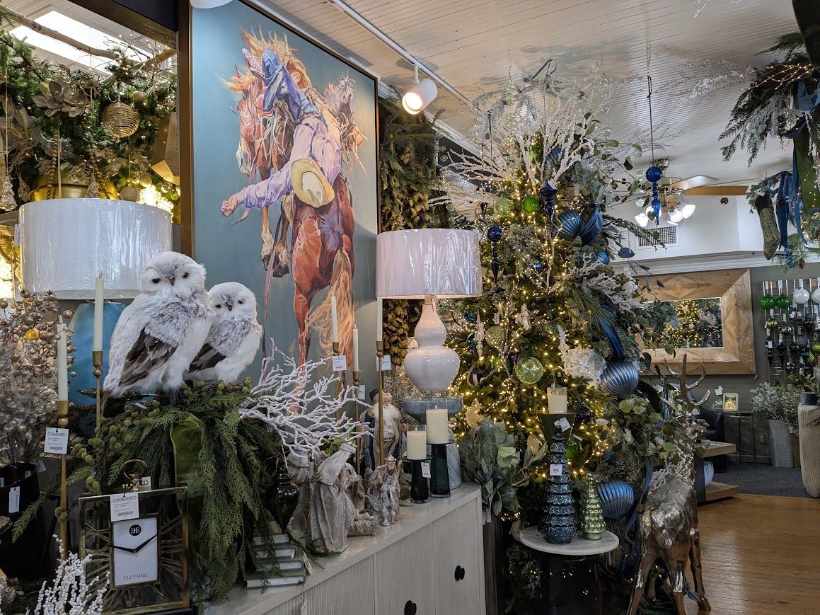 Festive home decor display with blue-and-white floral artwork, lit lamps, greenery, and mirrored accents