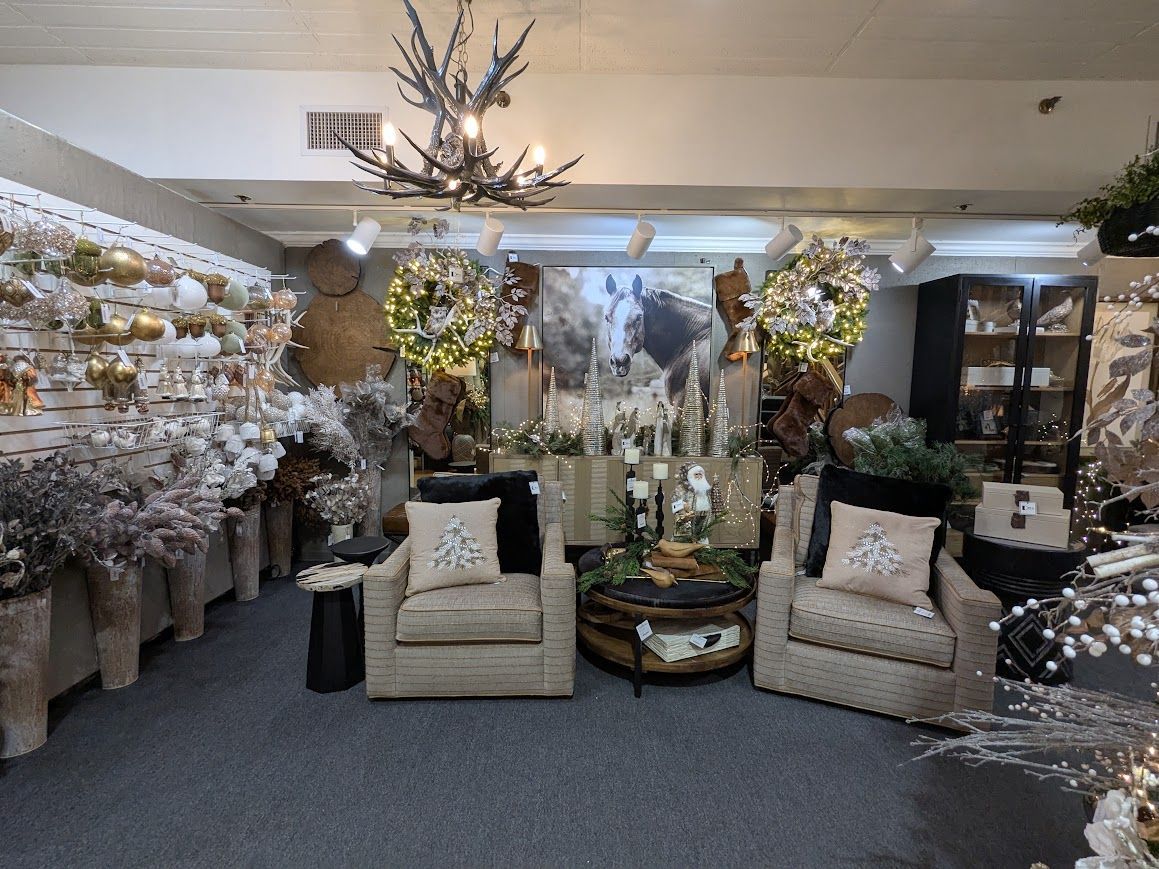 Floral home decor showroom with cream chairs, mirrored tables, and white blossom arrangements.