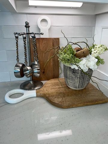 Kitchen counter with silver utensils, cutting boards, and a white flower arrangement in a striped vase