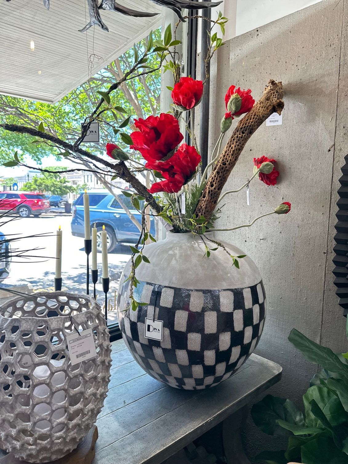 Red flowers in a black-and-white checkered vase on a windowsill outdoors