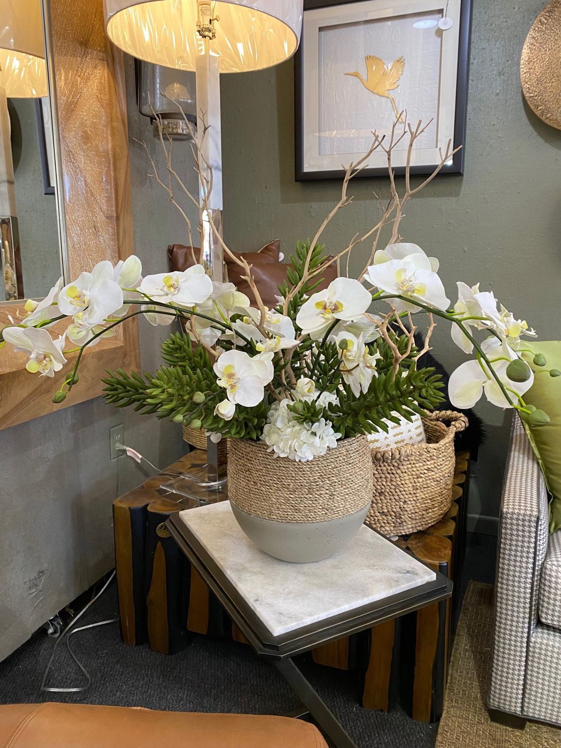 White orchid arrangement in woven baskets on a table in a home decor store