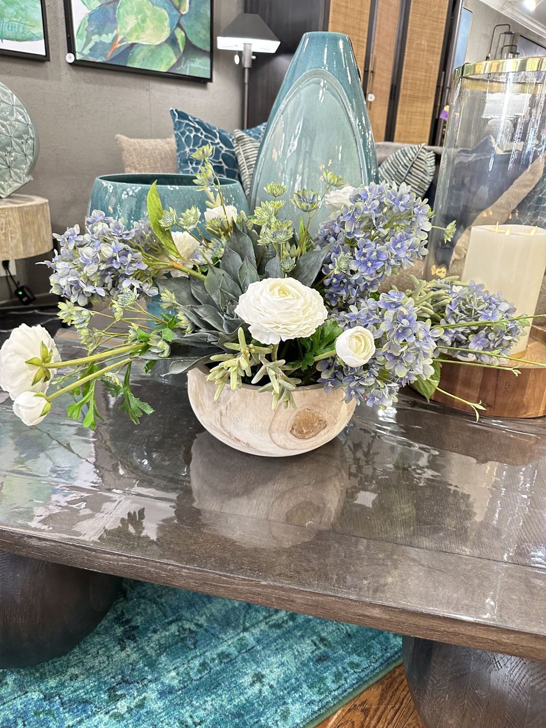 White and lavender floral arrangement in a decorative bowl on a table in a showroom