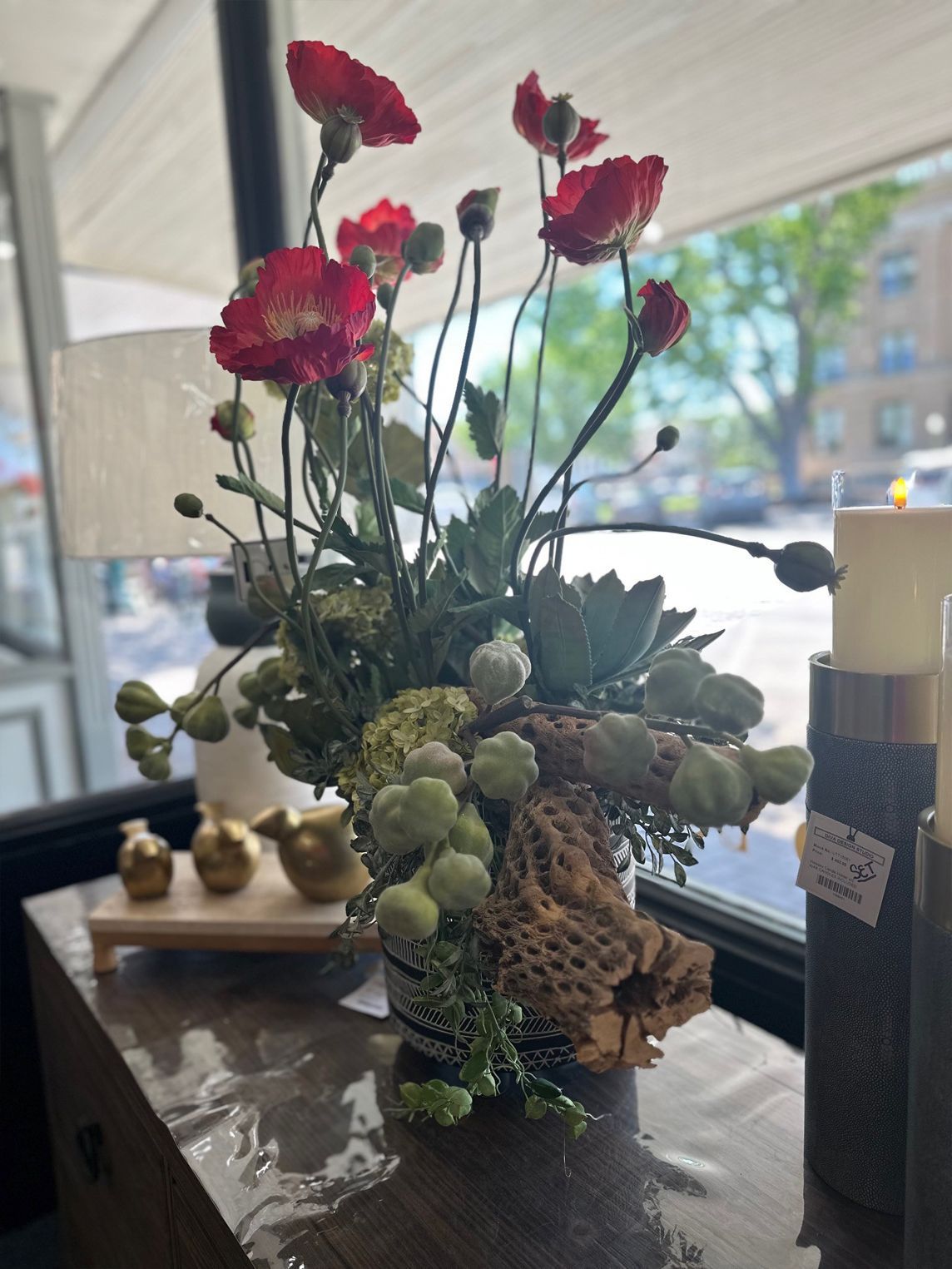 Pink flowers in a glass vase with succulents on a table by a window