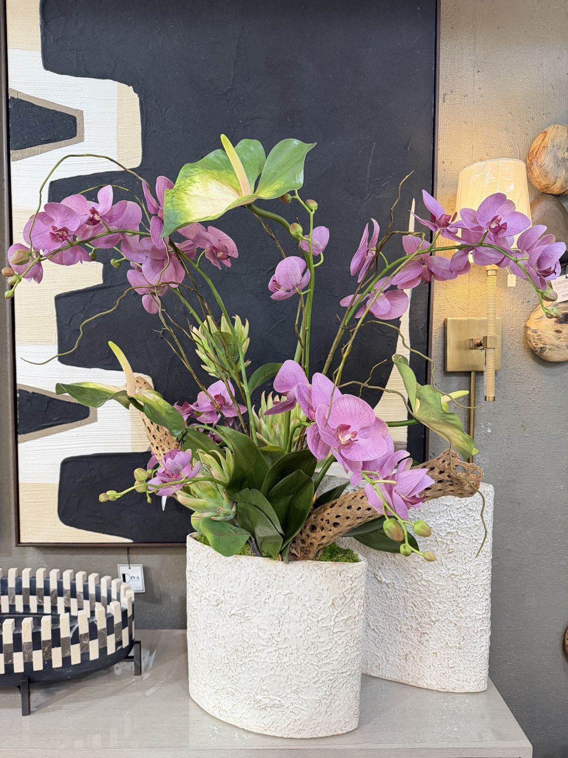 Purple flowers in white textured pots on a modern indoor display table.