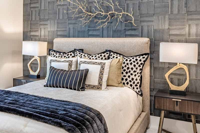 Modern bedroom with a tufted bed, layered pillows, blue accents, and matching bedside lamps
