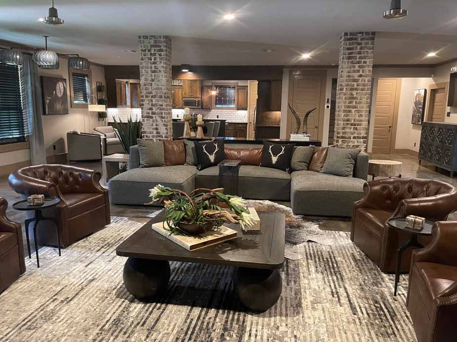 Spacious living room with sectional sofa, leather chairs, coffee table, and rustic stone columns