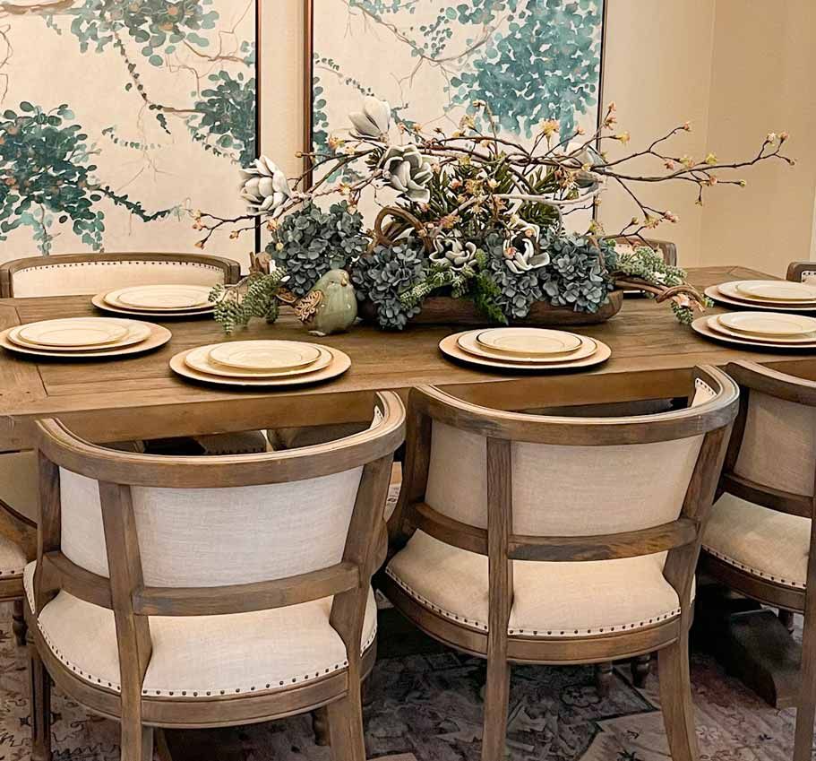 Elegant dining table with beige chairs, white plates, and blue floral centerpiece