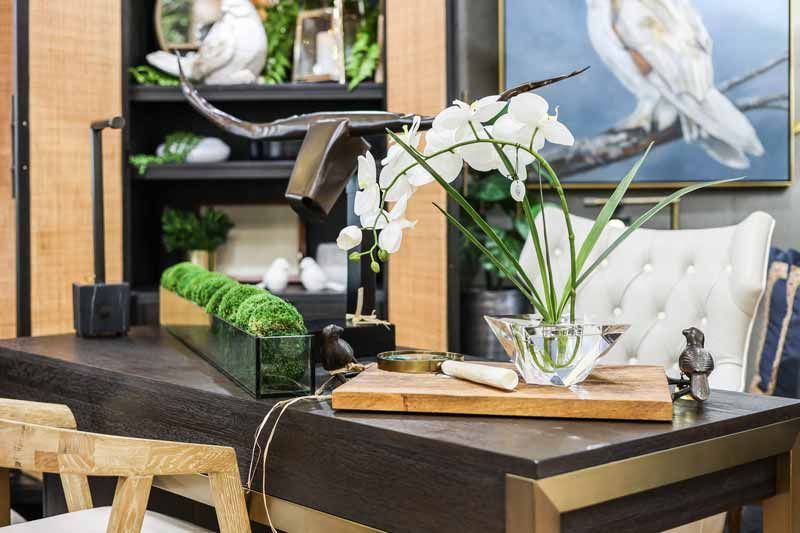 Modern desk with white orchids, books, and decor in a stylish office setting