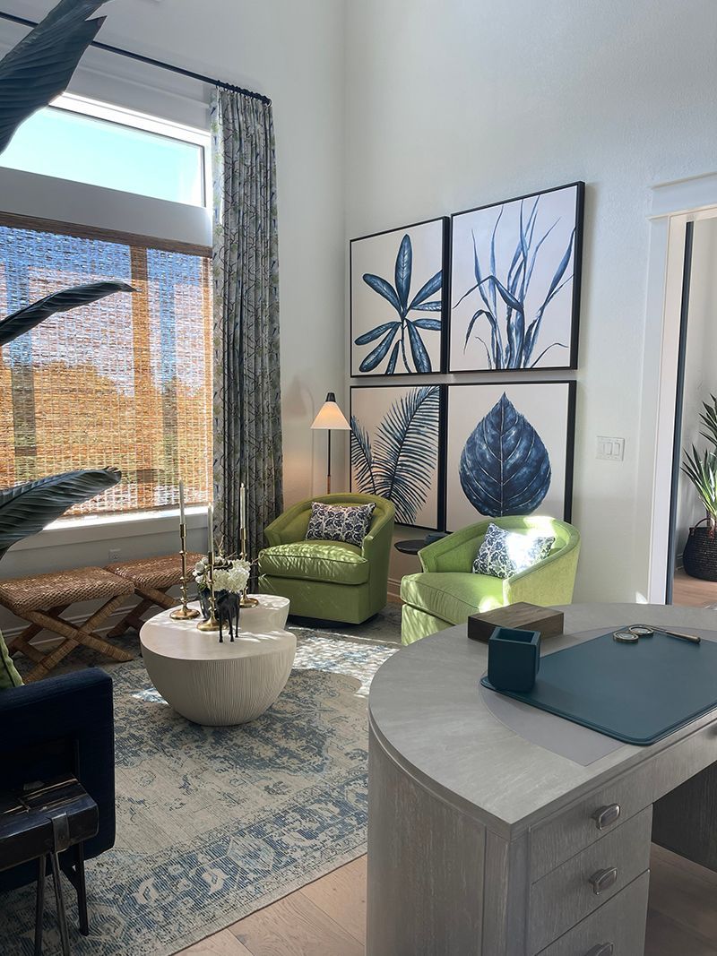 Bright modern living room with green chairs, abstract wall art, large window, and patterned rug