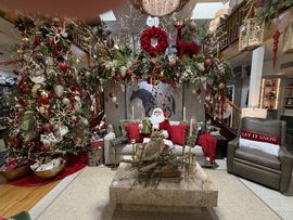 Festive holiday living room with a decorated tree, garlands, Santa figures, and red-accented sofas