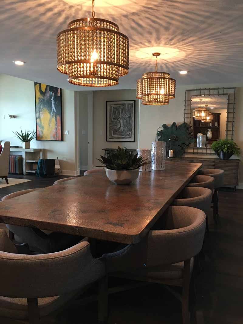 Modern dining room with long wooden table, upholstered chairs, and two woven pendant lights