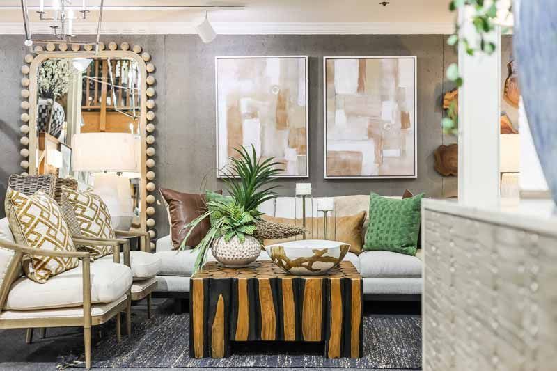 Bright living room with patterned chairs, sofa, coffee table, wall art, and greenery