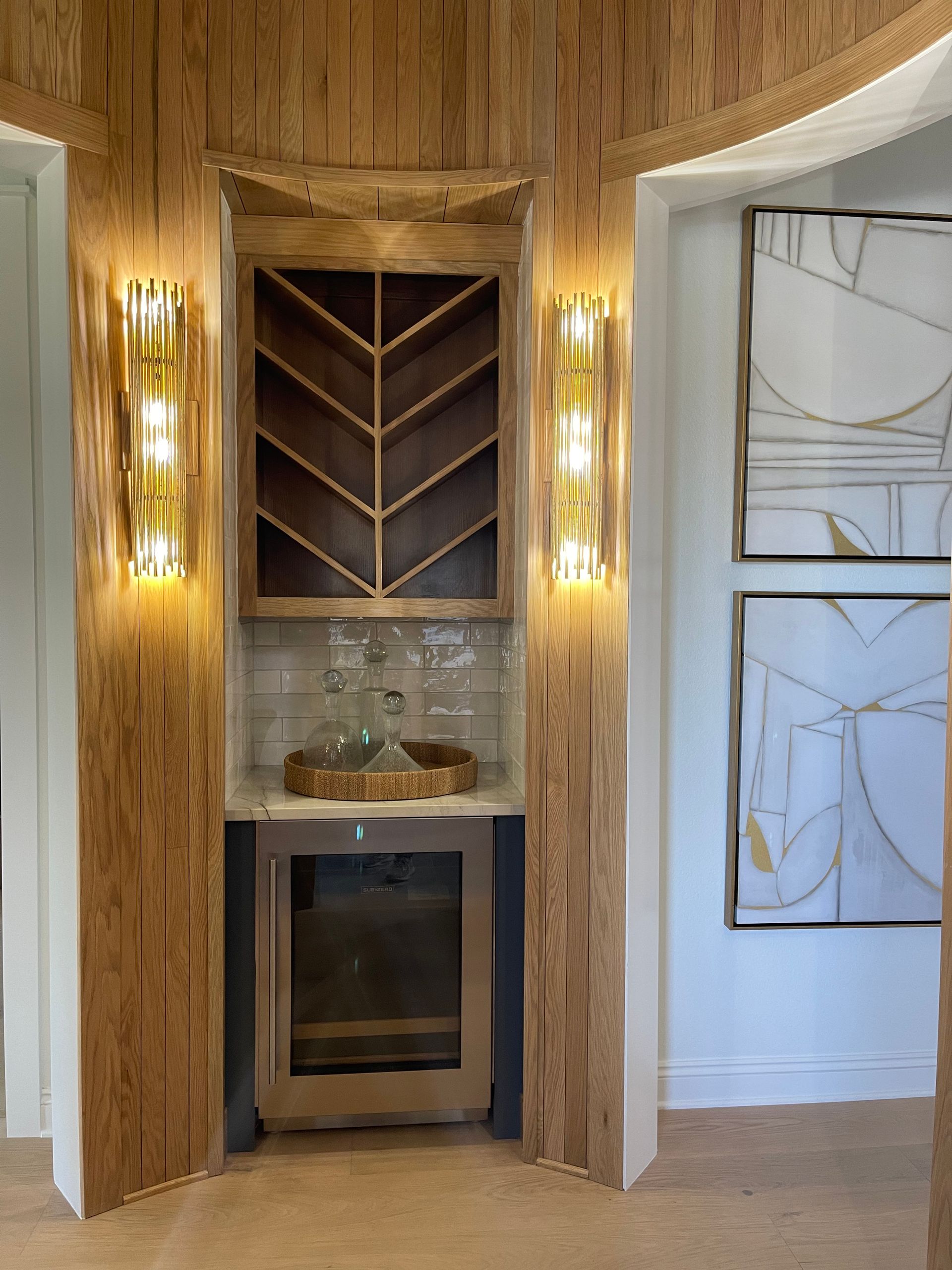 Built-in wood niche with wine rack, glass shelf, and small beverage fridge in a modern hallway