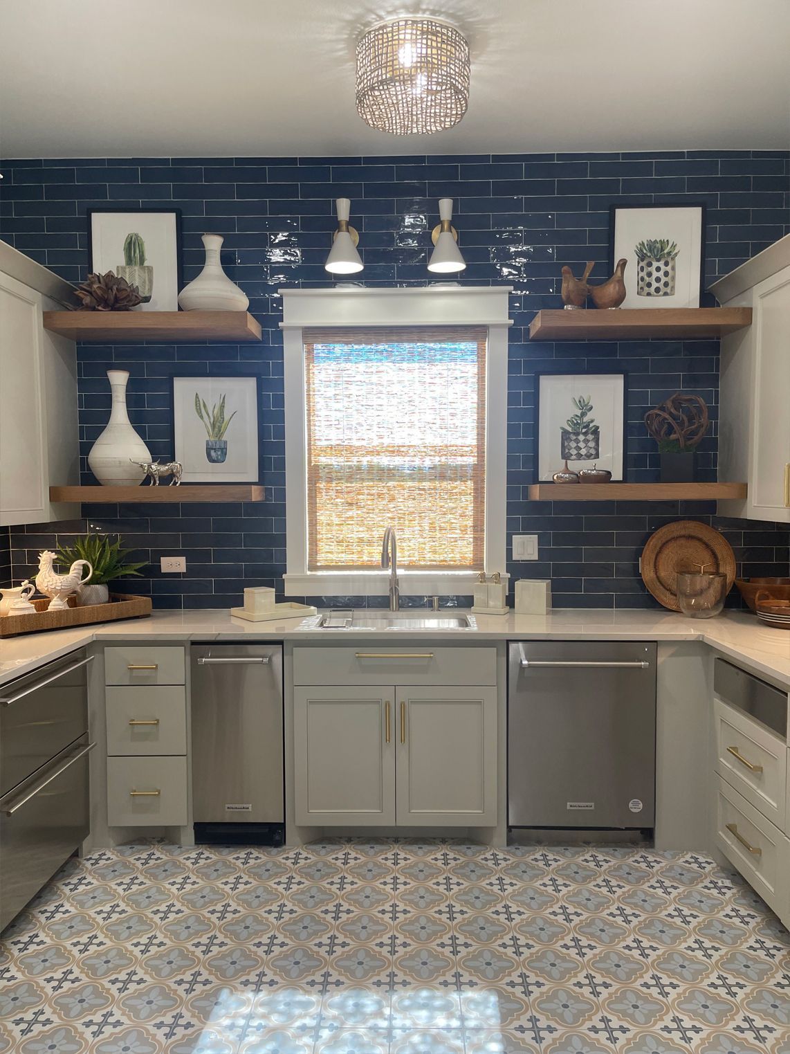 Modern kitchen with navy tile backsplash, open shelves, sink under window, and patterned floor tiles