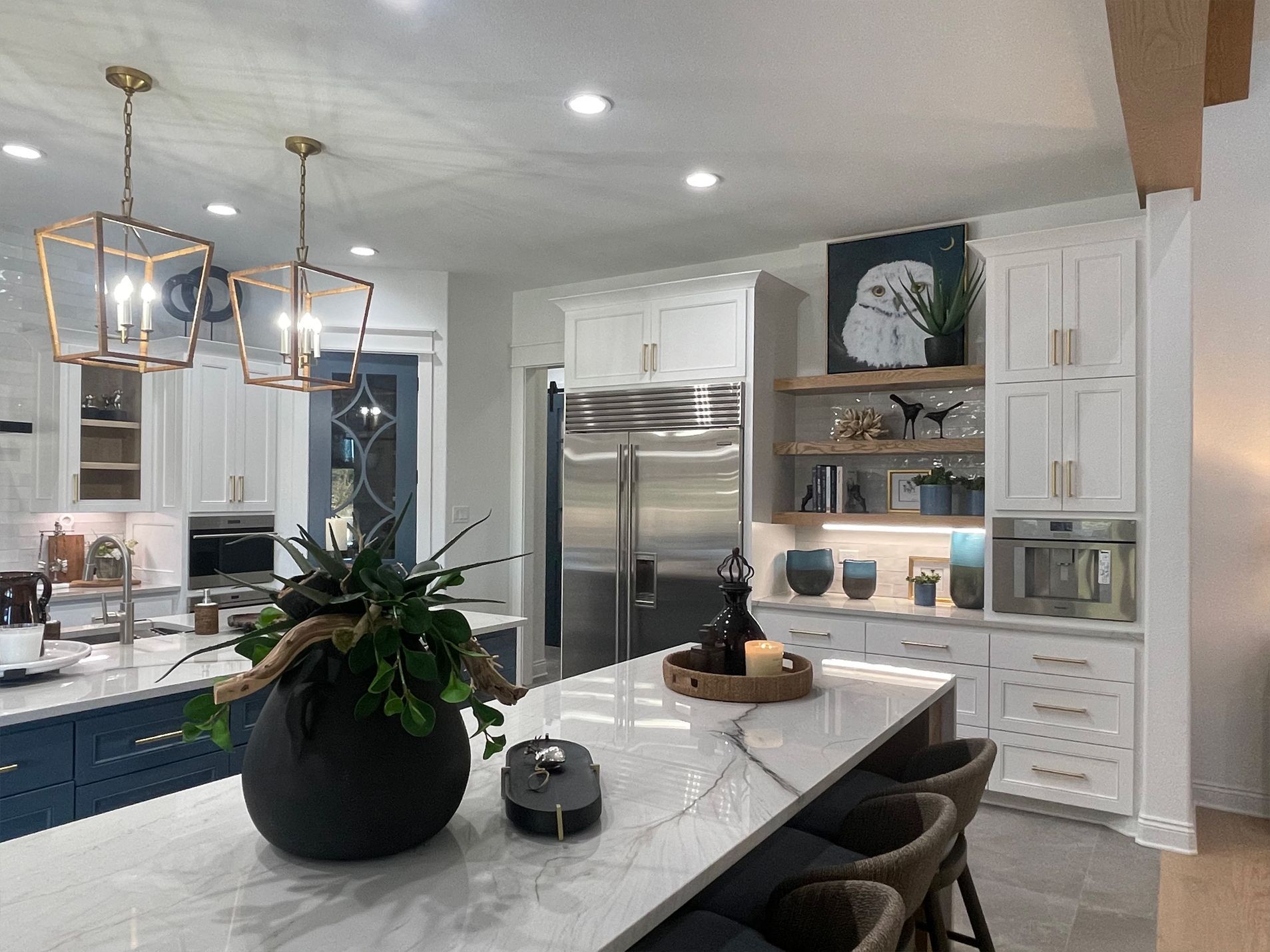 Bright modern kitchen with white cabinets, stainless fridge, island, and pendant lights