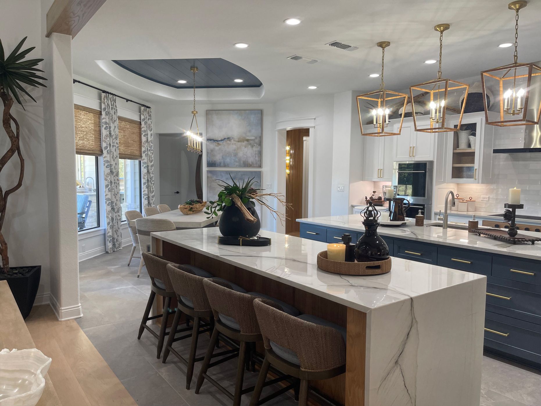 Bright modern kitchen with marble island, pendant lights, bar stools, and large windows
