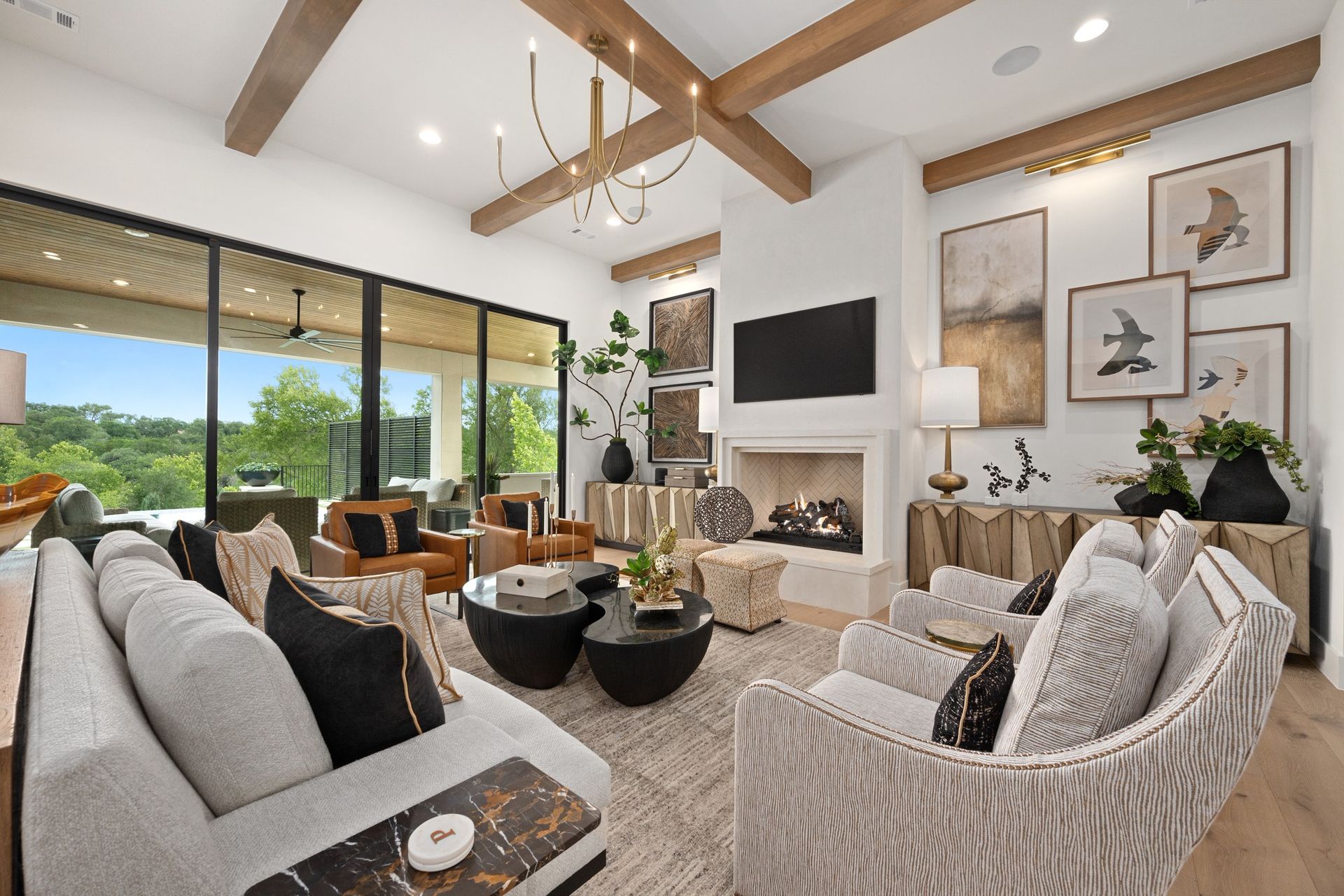 Bright open living room with vaulted wood beams, fireplace, large TV, and mountain-view windows
