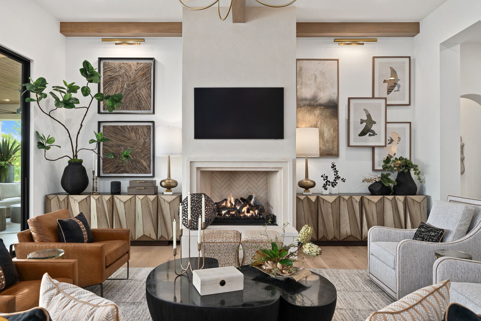 Modern living room with fireplace, wall-mounted TV, tan and gray chairs, and black coffee tables