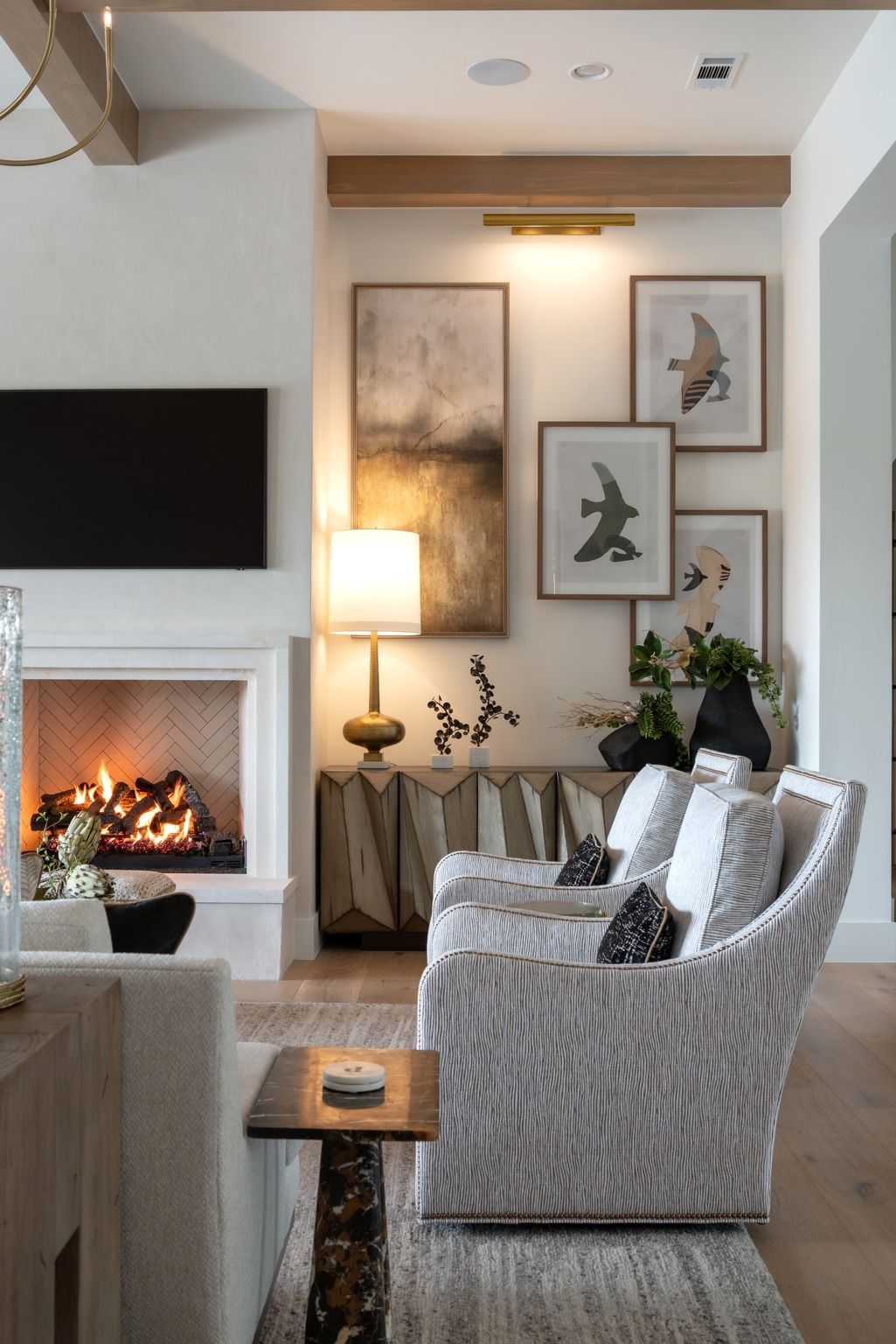 Cozy living room with lit fireplace, patterned chairs, and bird artwork on the wall