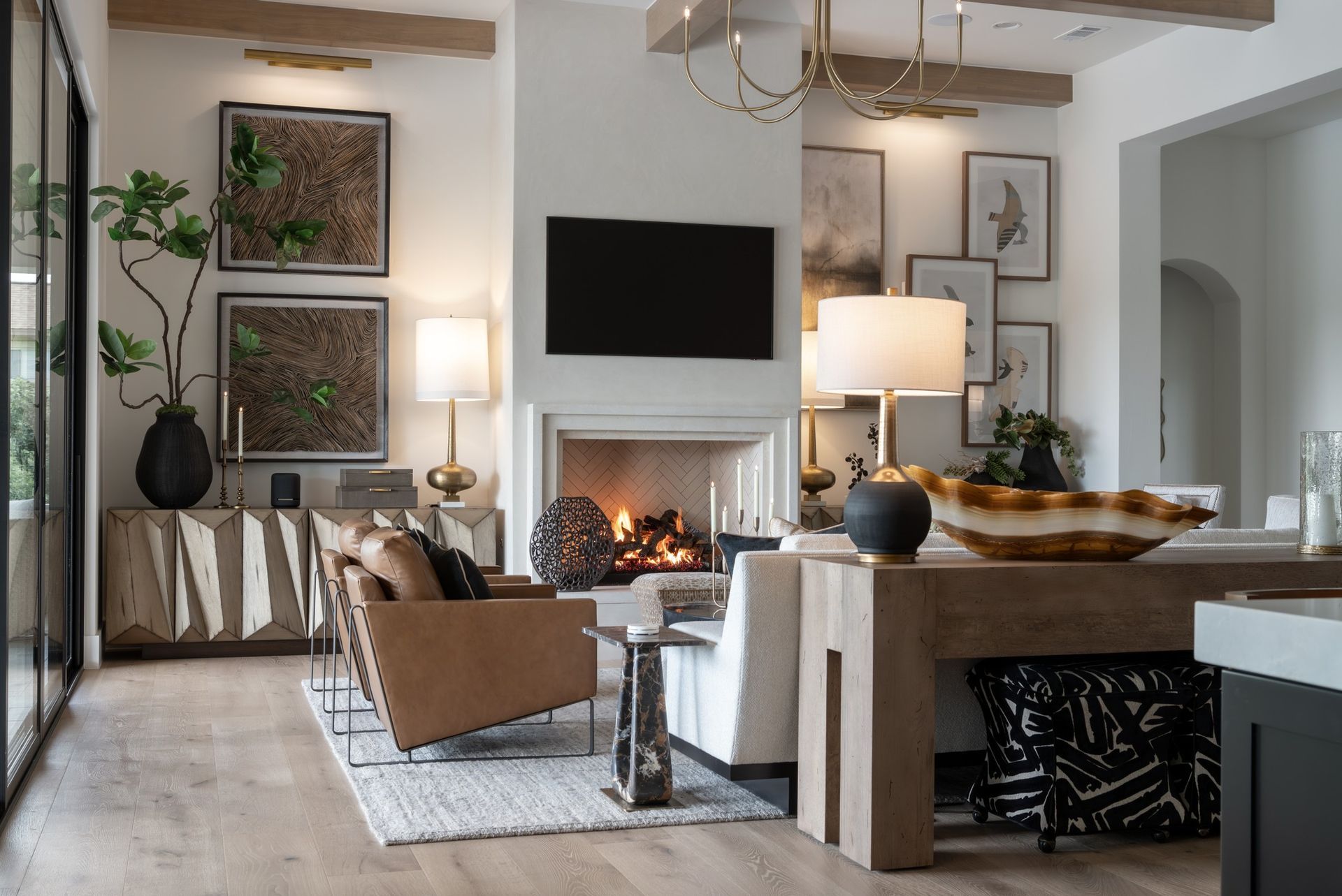 Modern living room with fireplace, wall-mounted TV, neutral furniture, and large framed art.