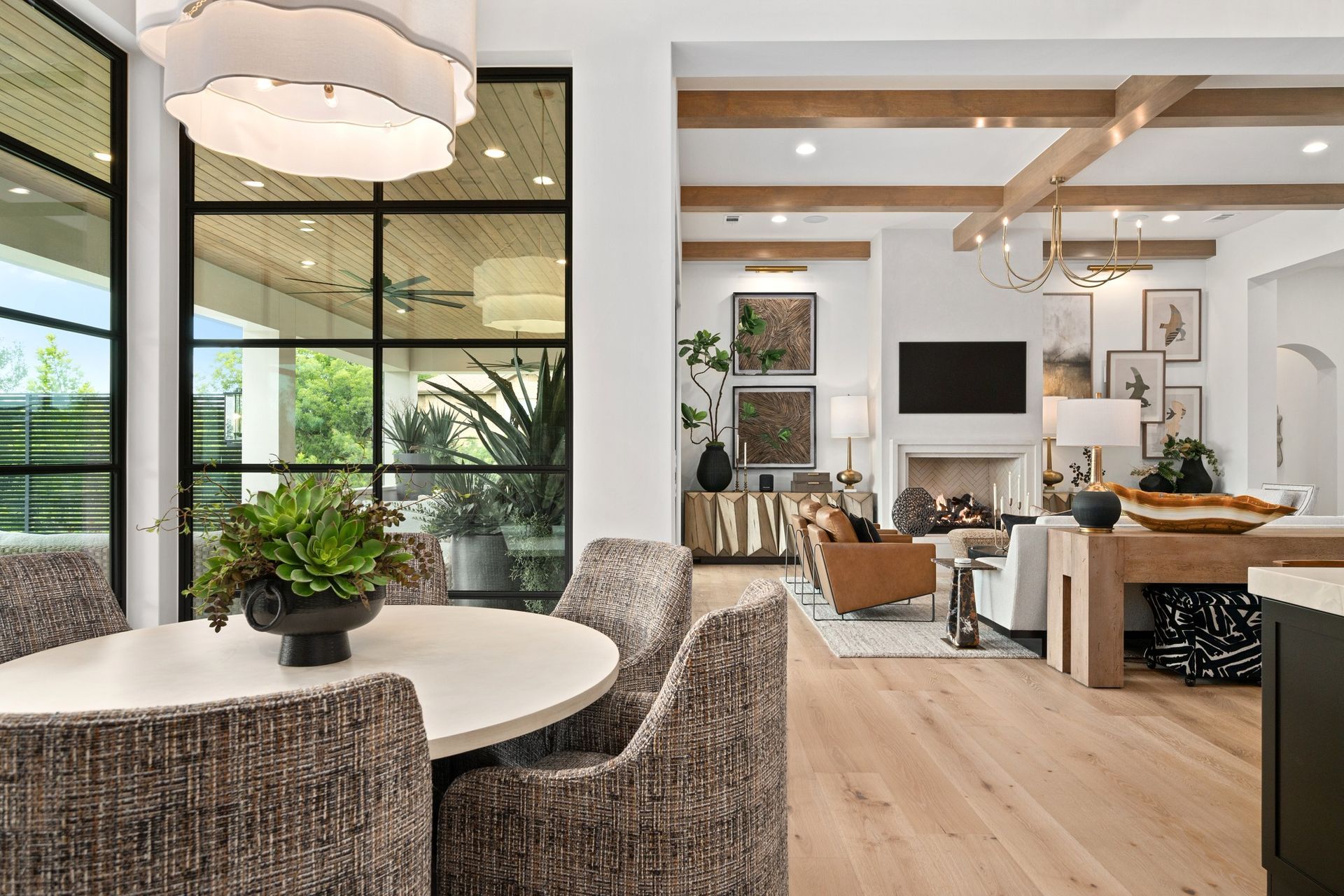 Modern open-concept dining and living room with wicker chairs, wood floors, and large windows