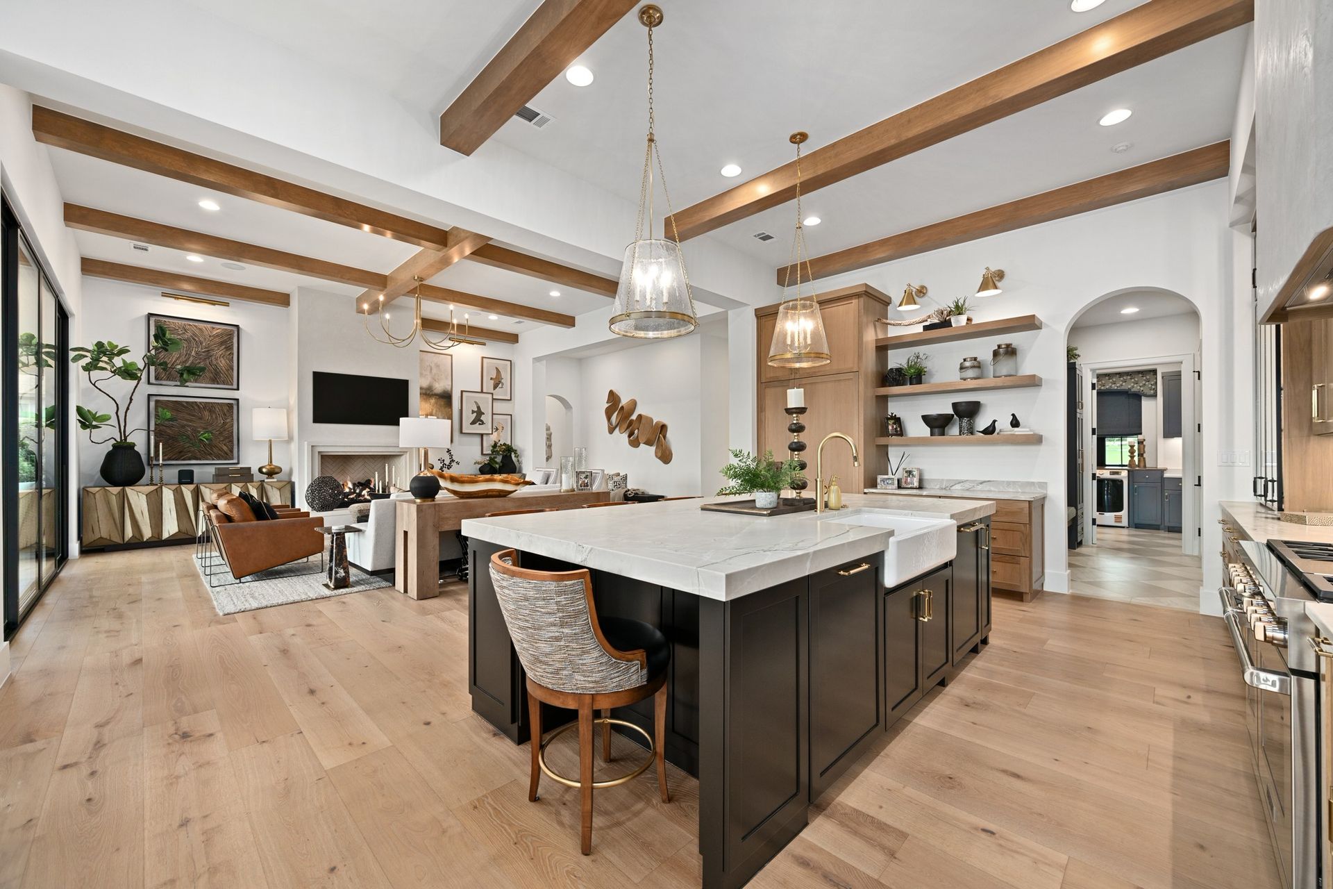 Bright modern open-plan kitchen and living room with wood beams, island, and large windows