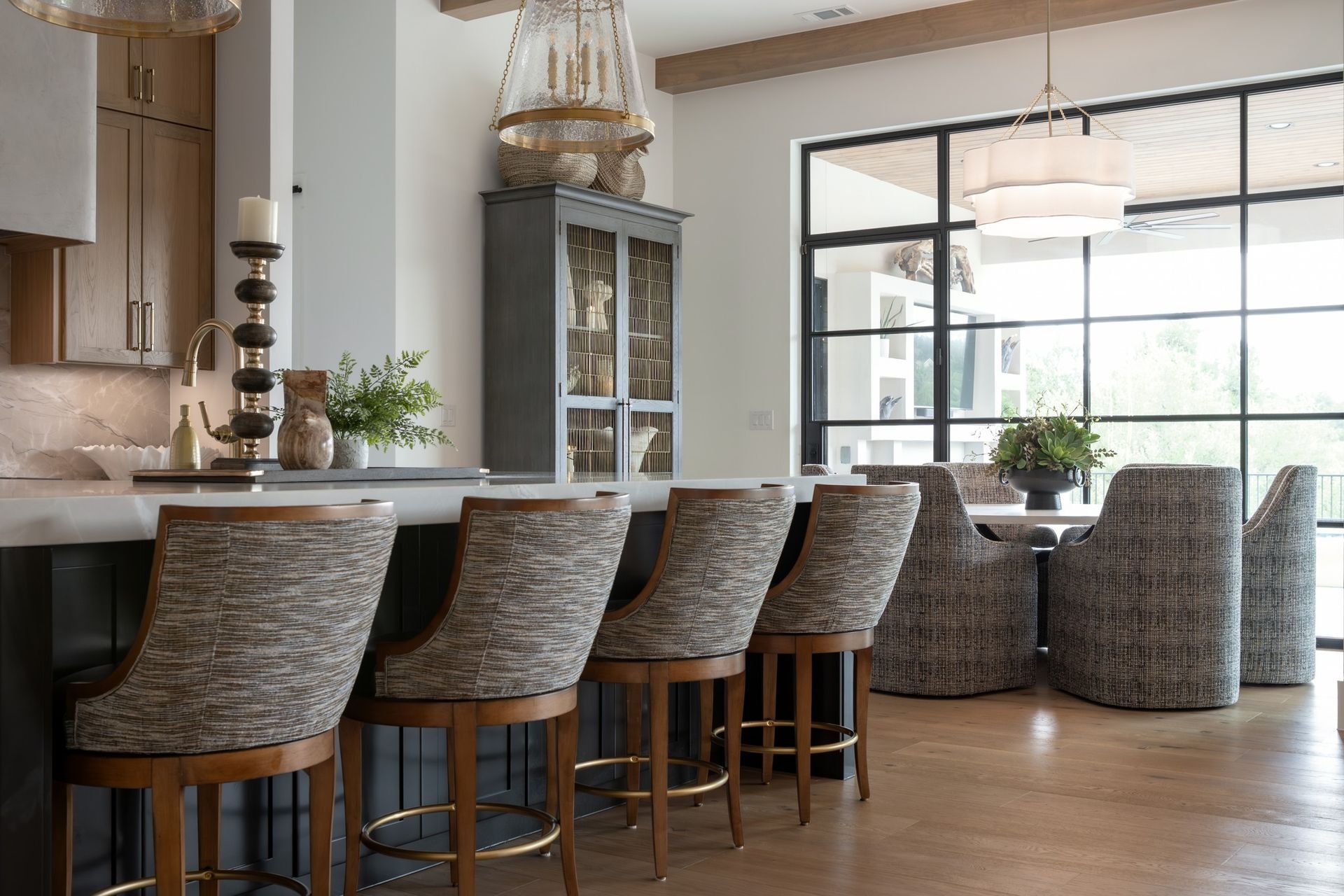 Modern kitchen with woven bar stools, island seating, and a bright dining area with large windows