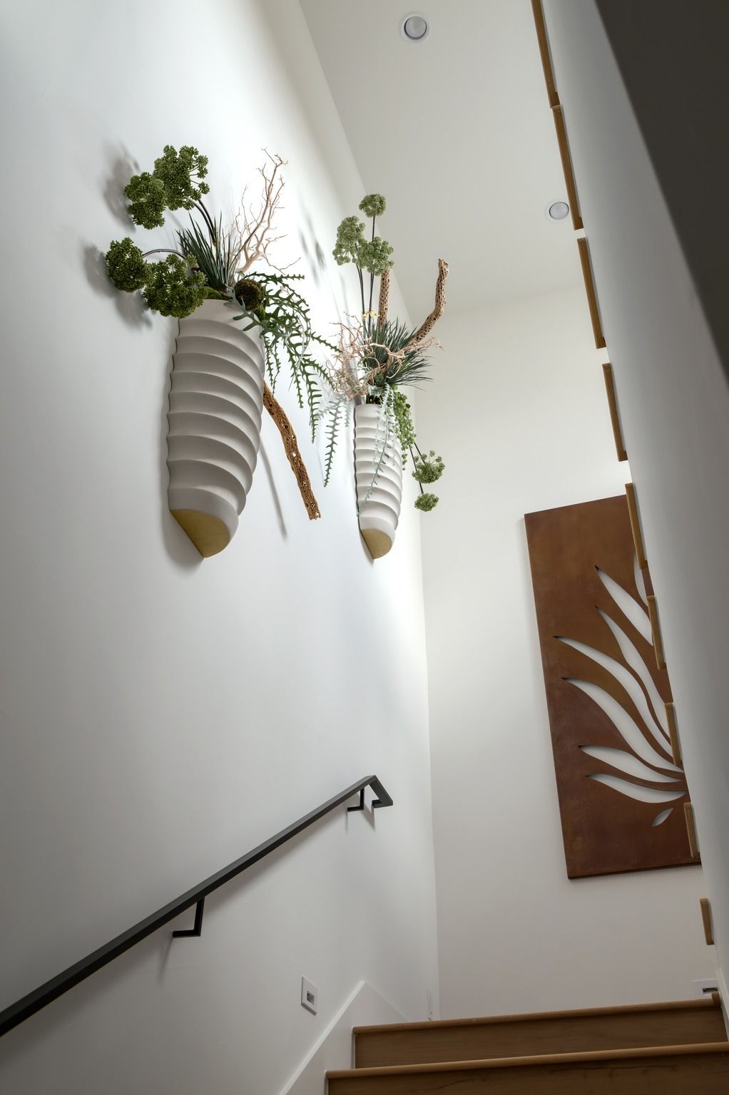 Modern stairwell with hanging striped planters and a brown wall art panel