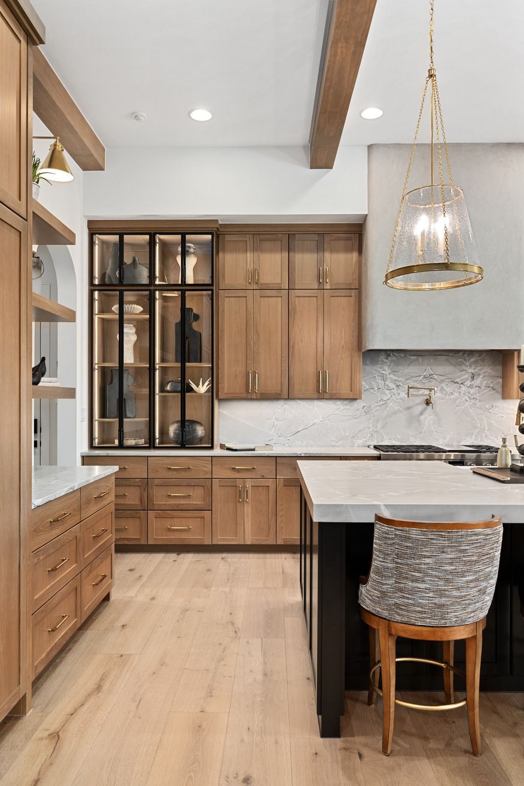 Modern kitchen with wood cabinets, marble island, black accents, and a hanging glass pendant light