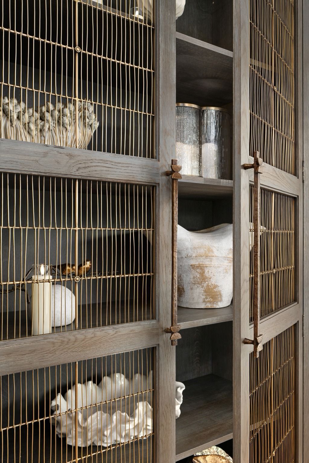 Rusty metal cages with shelves holding white ceramic jars and small decorative objects