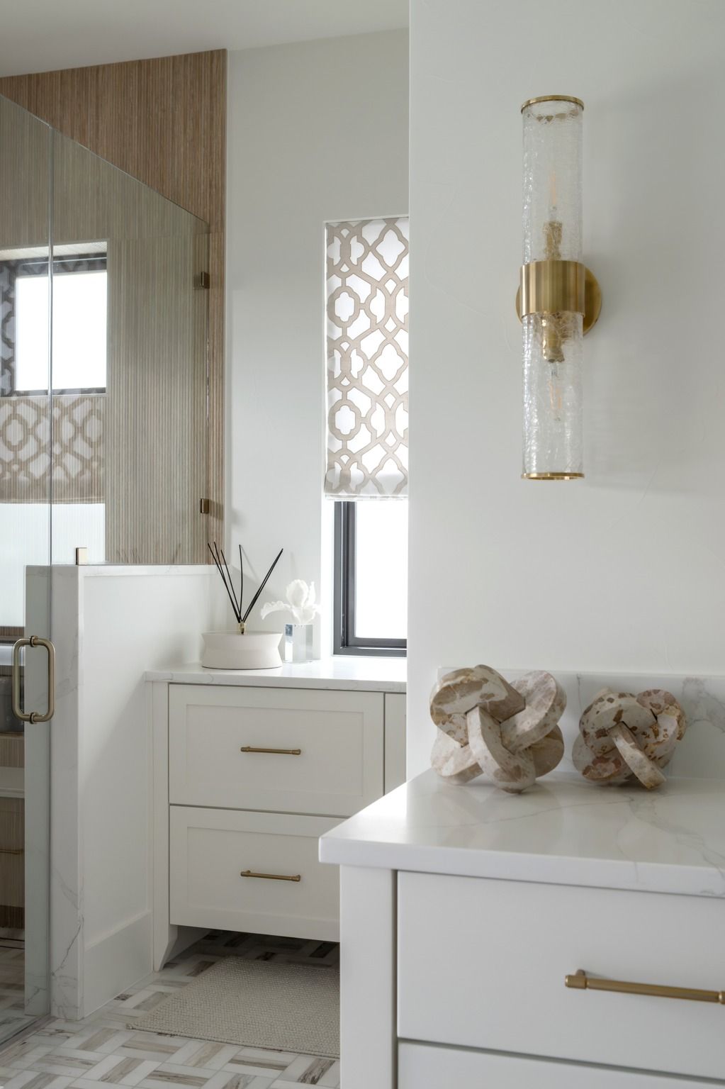Bright modern bathroom with white vanity, gold fixtures, and decorative sculpture on the counter